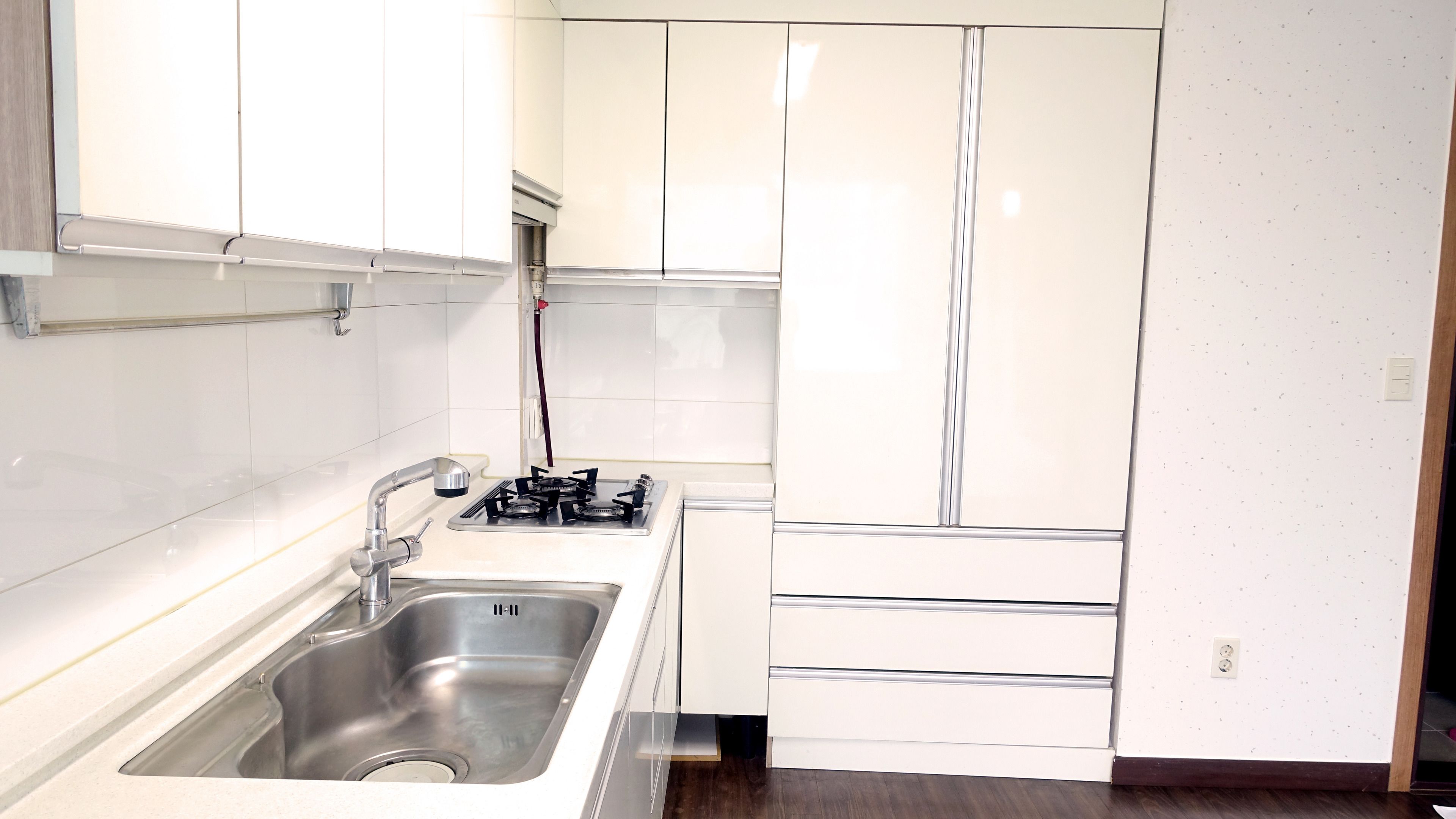 A modern kitchen with a stainless steel sink, a gas stove, and white cabinetry.