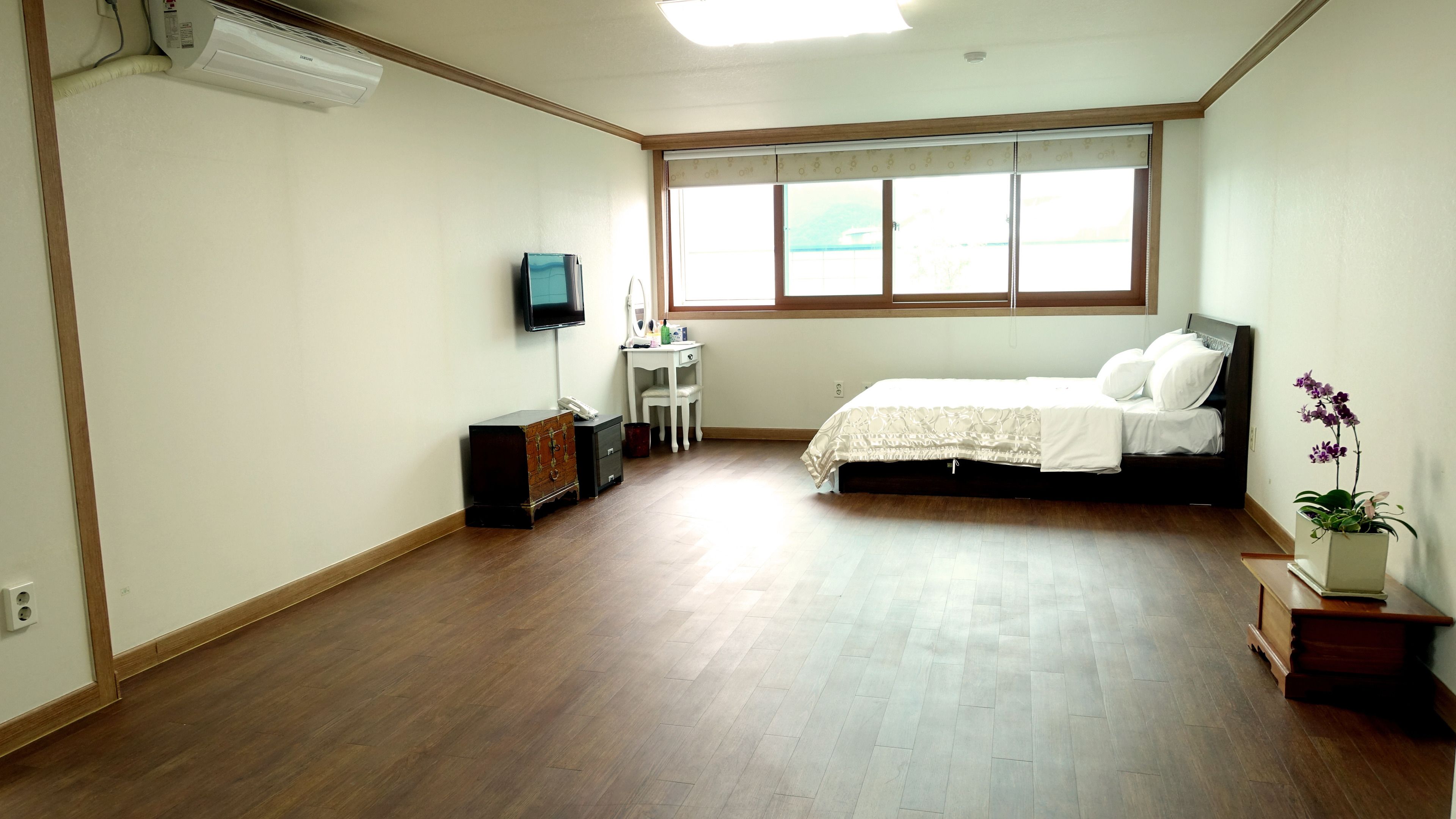 Un dormitorio con cama, escritorio, silla, televisión y ventana.