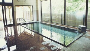 Une piscine intérieure avec des parois en verre transparent, une horloge bien visible et un sol carrelé.