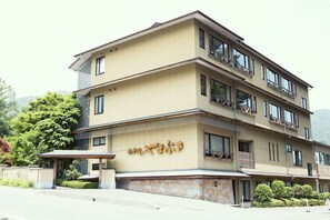 A multi-story hotel with a beige facade, balconies, and a stone base. - Hotel Yamabuki (Komagane)
