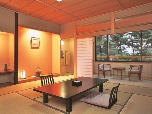 A traditional Japanese-style room with tatami flooring, a low table, and chairs.