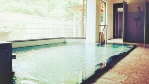 Une piscine intérieure avec des parois en verre transparent, un sol carrelé et un espace douche.
