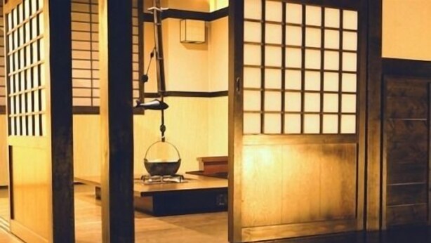 Une pièce de style japonais traditionnel, avec un sol recouvert de tatamis, une porte coulissante en papier de riz (shoji) et une lanterne suspendue.