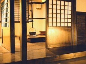A traditional Japanese room with tatami flooring, a shoji screen door, and a hanging lantern.