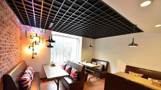 A modern interior with a brick wall, a wooden bench with Union Jack pillows, a table, and a bench with a small table. - Beijing RJ Brown Hotel (Beijing)