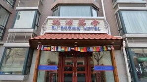 The exterior of RJ Brown Hotel with a sign in both English and Chinese, a tiled roof, and two glass doors with blue signage. - Beijing RJ Brown Hotel (Beijing)