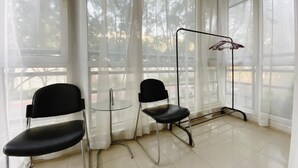 A room with two black chairs, a small round table, and a hanging clothes rack. - Beijing RJ Brown Hotel (Beijing)
