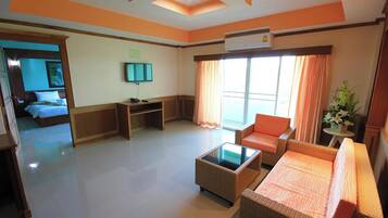 A hotel room with a bed, a sofa, a coffee table, a TV, and a window with curtains.