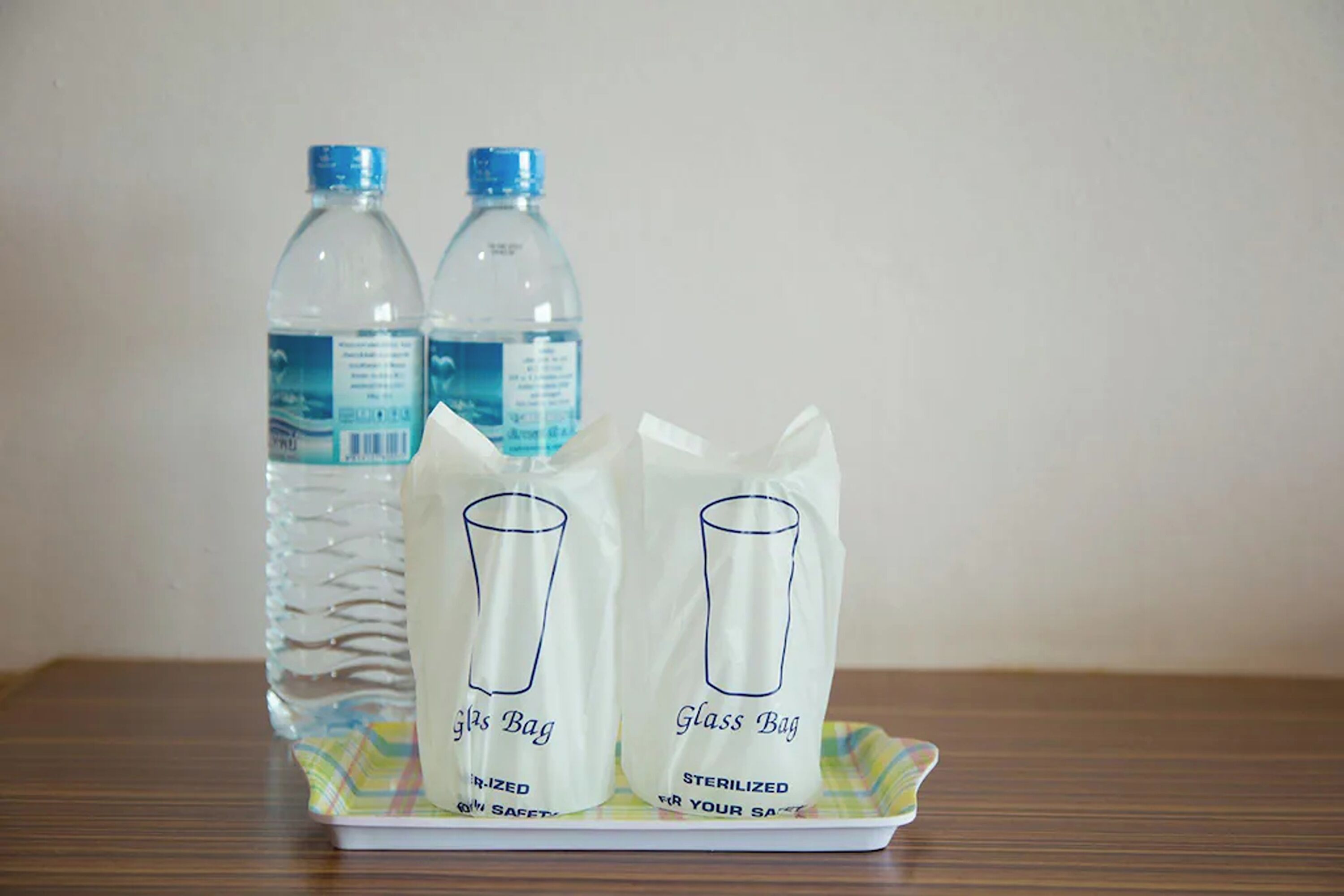 Dos botellas de agua y dos bolsas de vidrio sobre una bandeja.