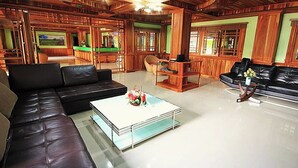 Un salón amplio con un sofá de cuero negro grande, una mesa de centro blanca y paneles de madera.