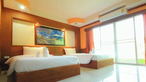Una habitación de hotel con dos camas de madera, un cuadro grande en la pared y un ventanal con cortinas.