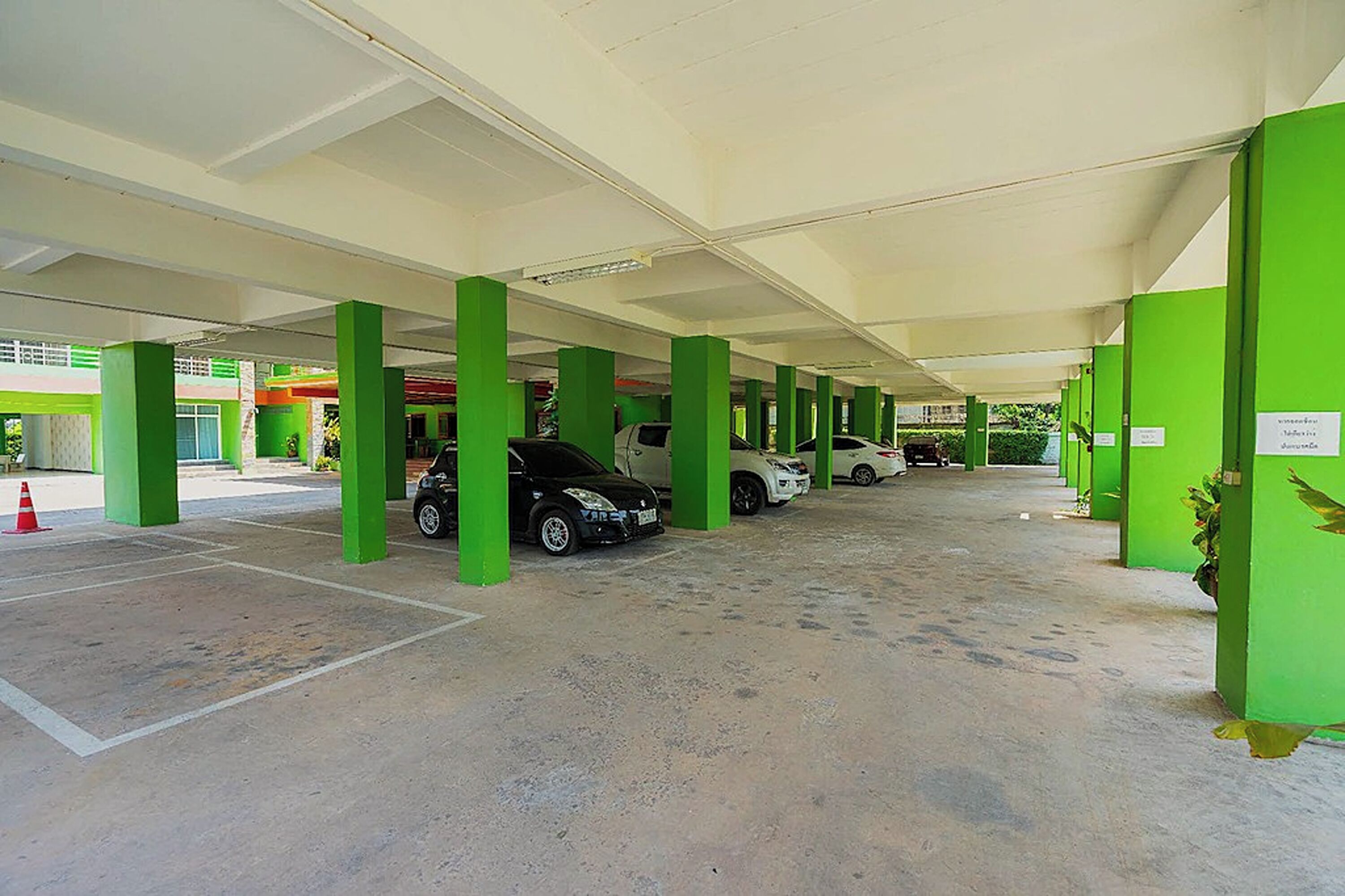 Un estacionamiento interior con pilares verdes y varios automóviles estacionados.