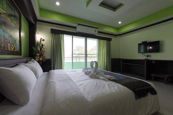 Habitación de hotel con una cama grande, televisión de pantalla plana, escritorio y ventana con cortinas.
