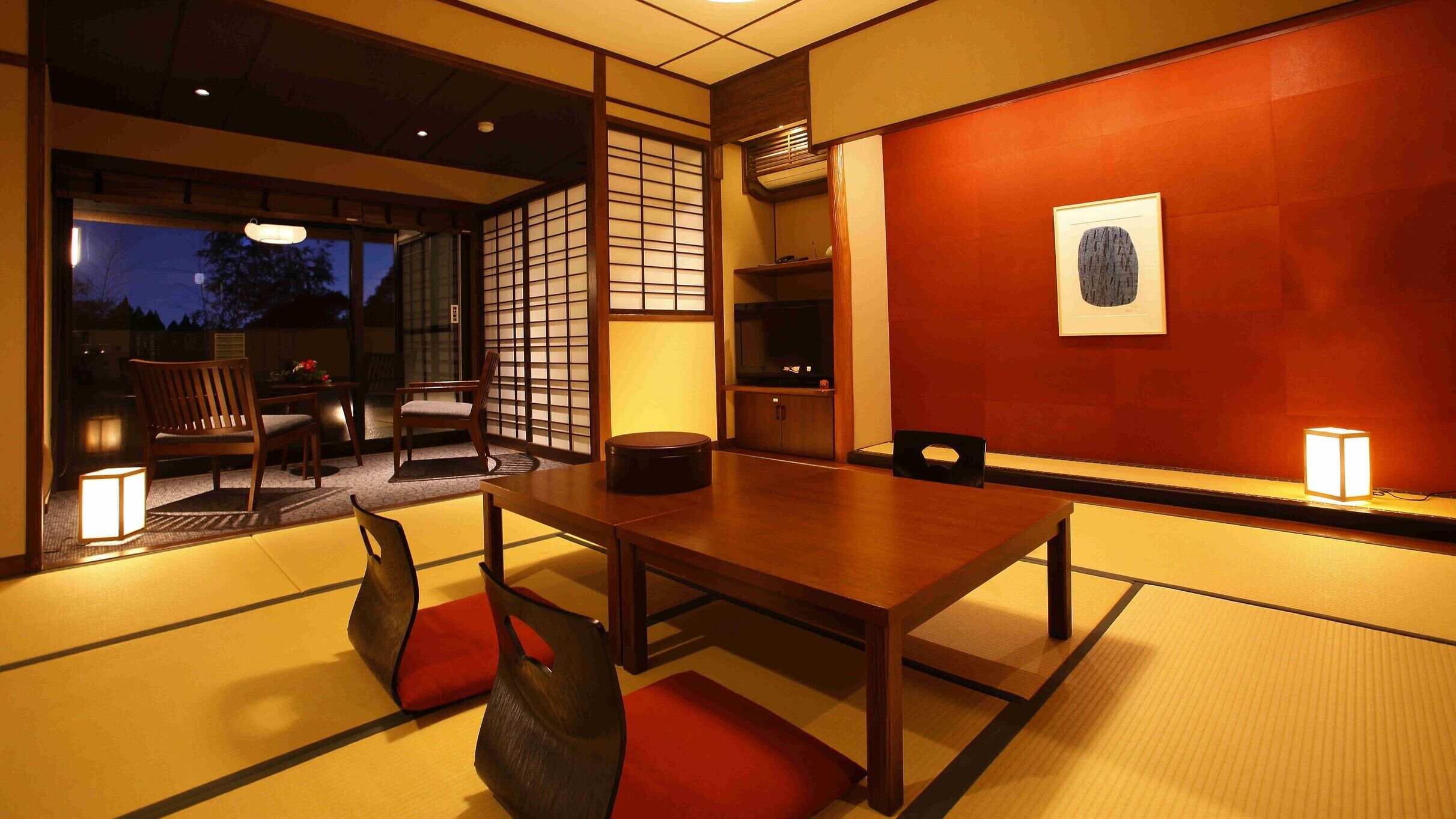 A traditional Japanese room with tatami flooring, a low table, and a television.