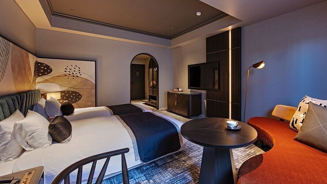 A hotel room with a bed, a desk, a TV, and a sofa.