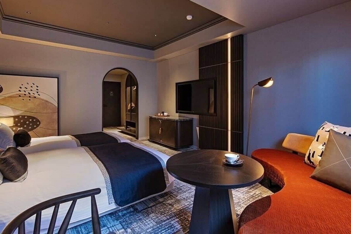 Una habitación de hotel con cama, escritorio, televisor y sofá.