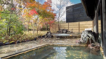 A traditional Japanese garden with a stone pool, koi fish, and autumn foliage.