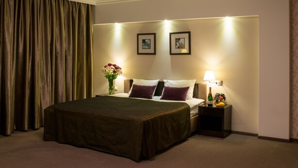 A hotel room with a large bed, a nightstand with a lamp, and a vase with flowers.