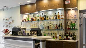 Een bar met kasten vol drankflessen, een kassa en een koffieapparaat.