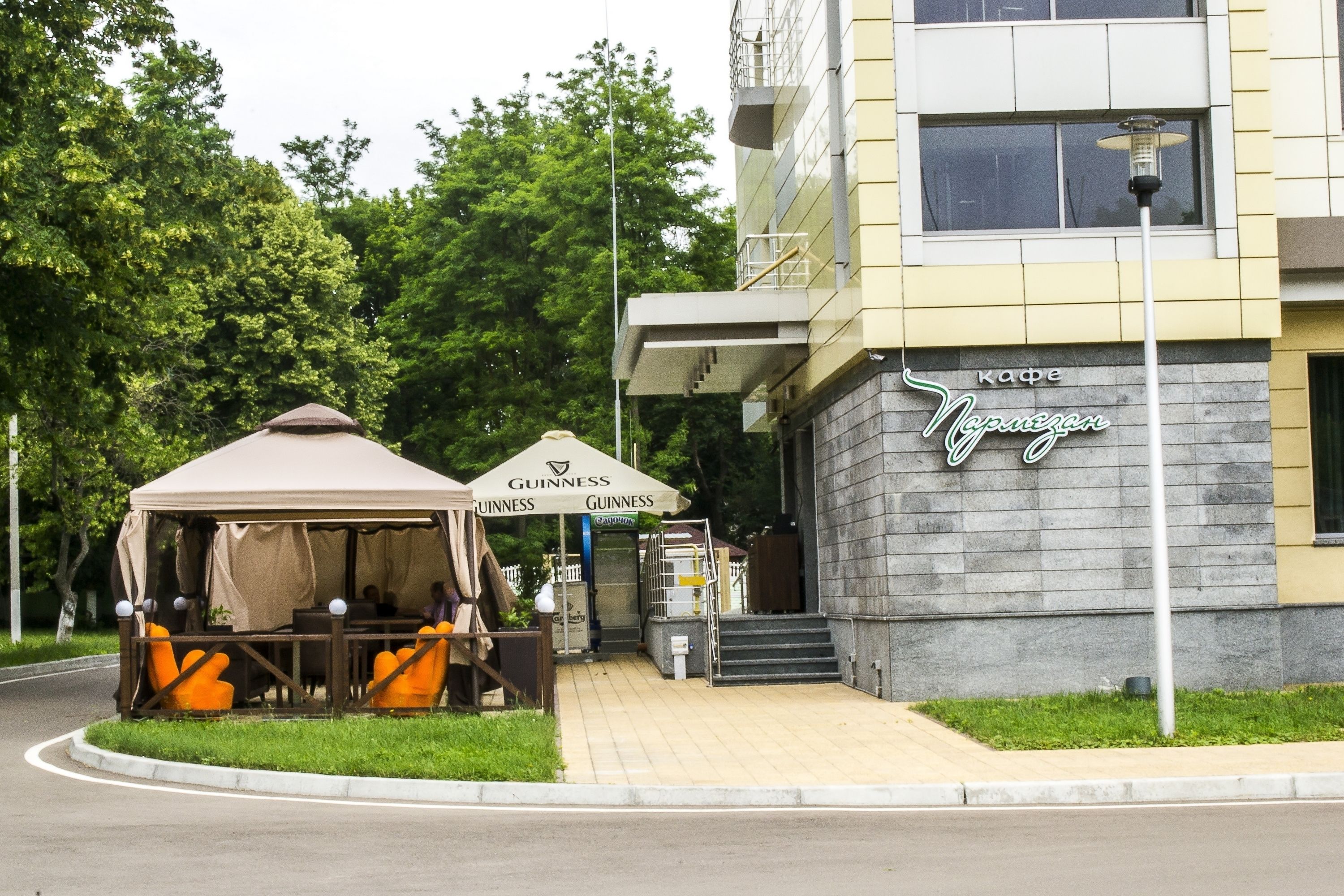 Un edificio con un cartello che riporta "Cafe Nerezgan" e un'area salotto all'aperto coperta da una tenda, con la scritta "Guinness".
