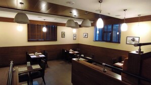 A restaurant interior with wooden paneling, pendant lighting, and framed pictures on the walls.
