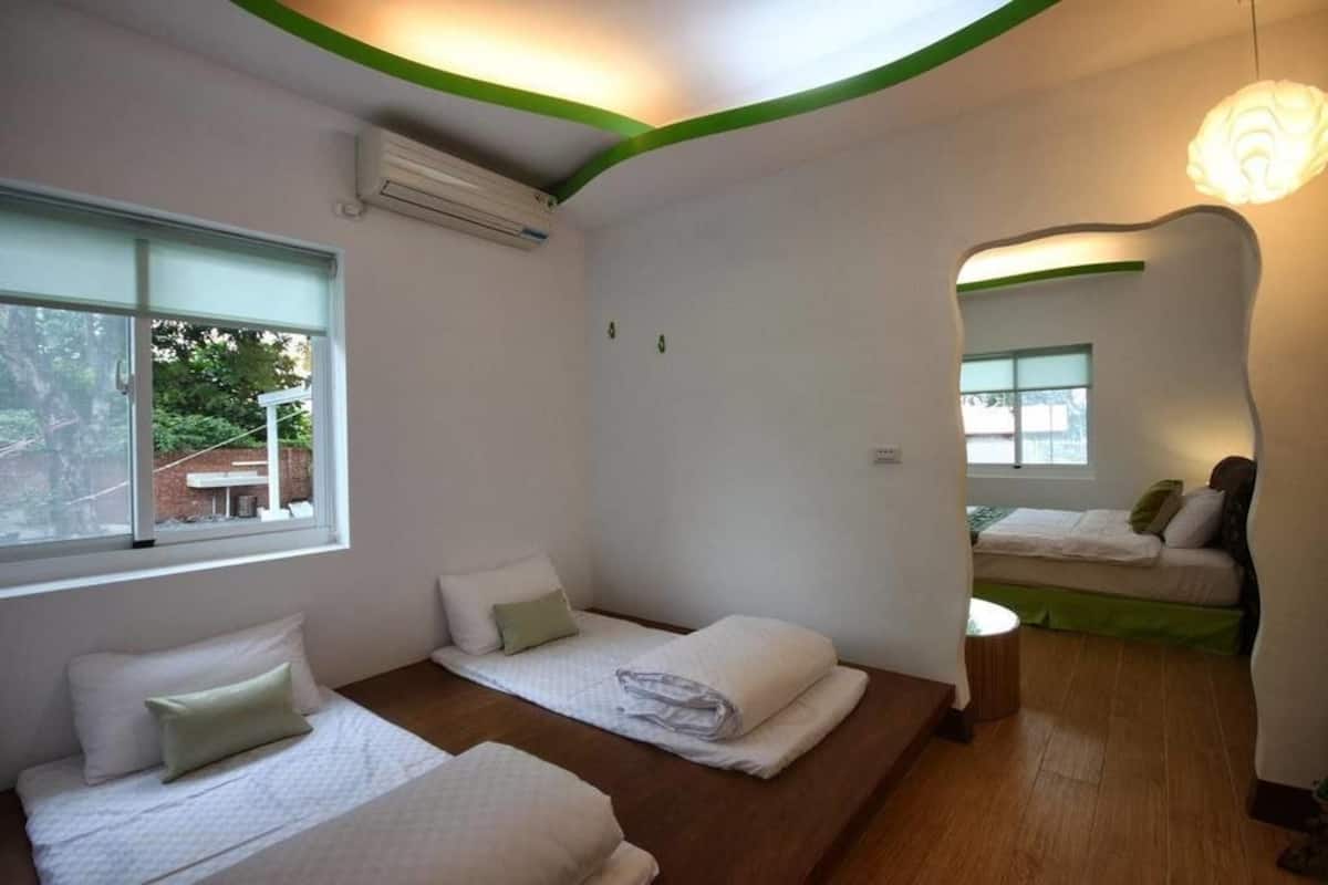 A room with two beds, a small table, and a mirror.
