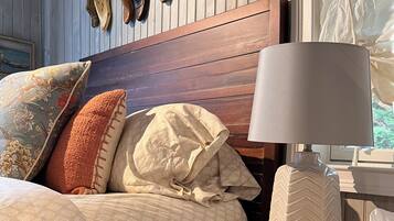 Una cama con varias almohadas, cabecero de madera y una lámpara de noche.