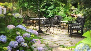 A garden patio with stone steps, a table and chairs, and a large umbrella. - Frederick William House (Falmouth)