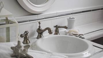 Een badkamer met een wit wastafelmeubel, twee kraanwerk, een spiegel en een handdoekhouder.