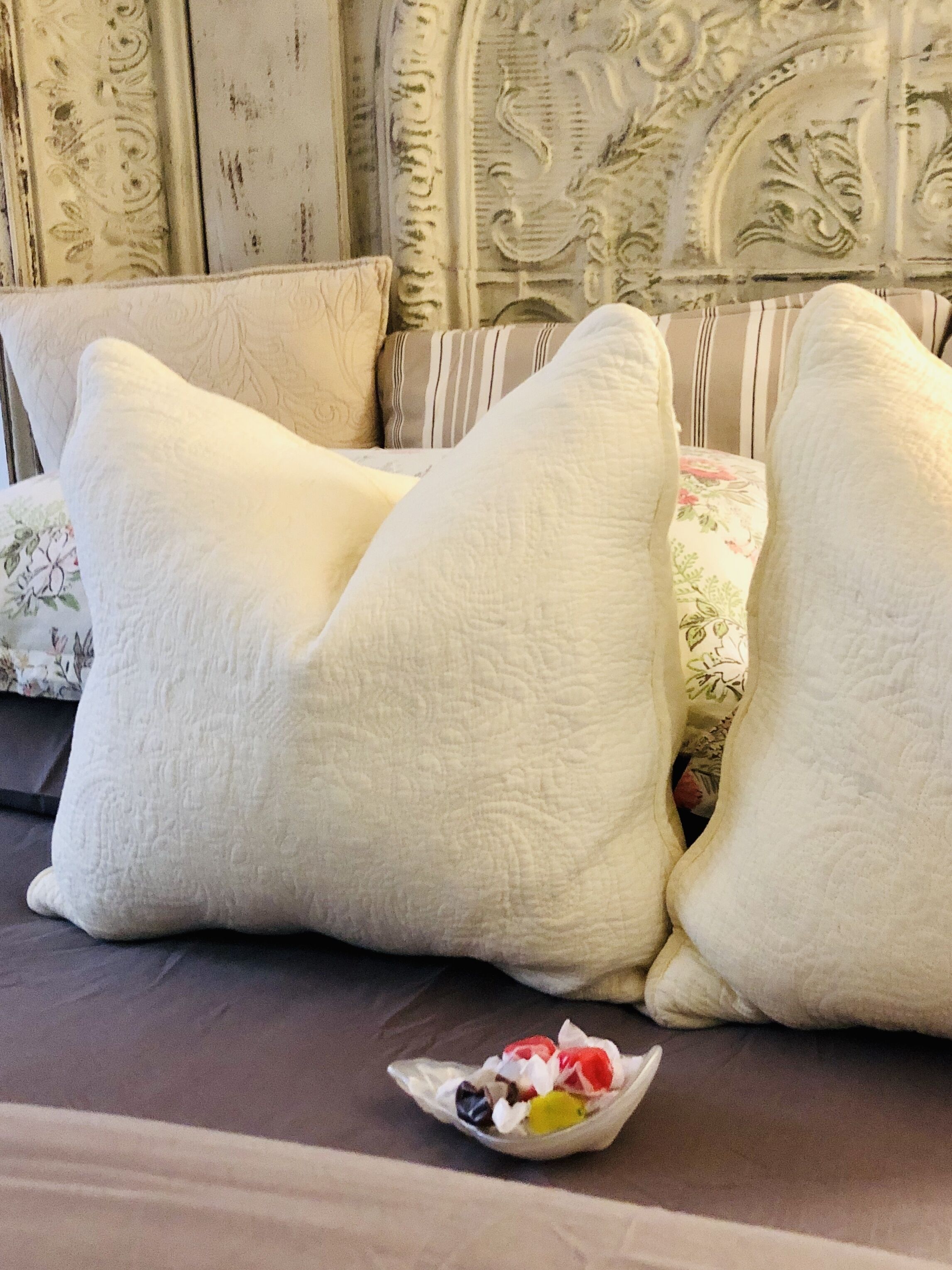 A bed with large white pillows and a floral-patterned blanket.