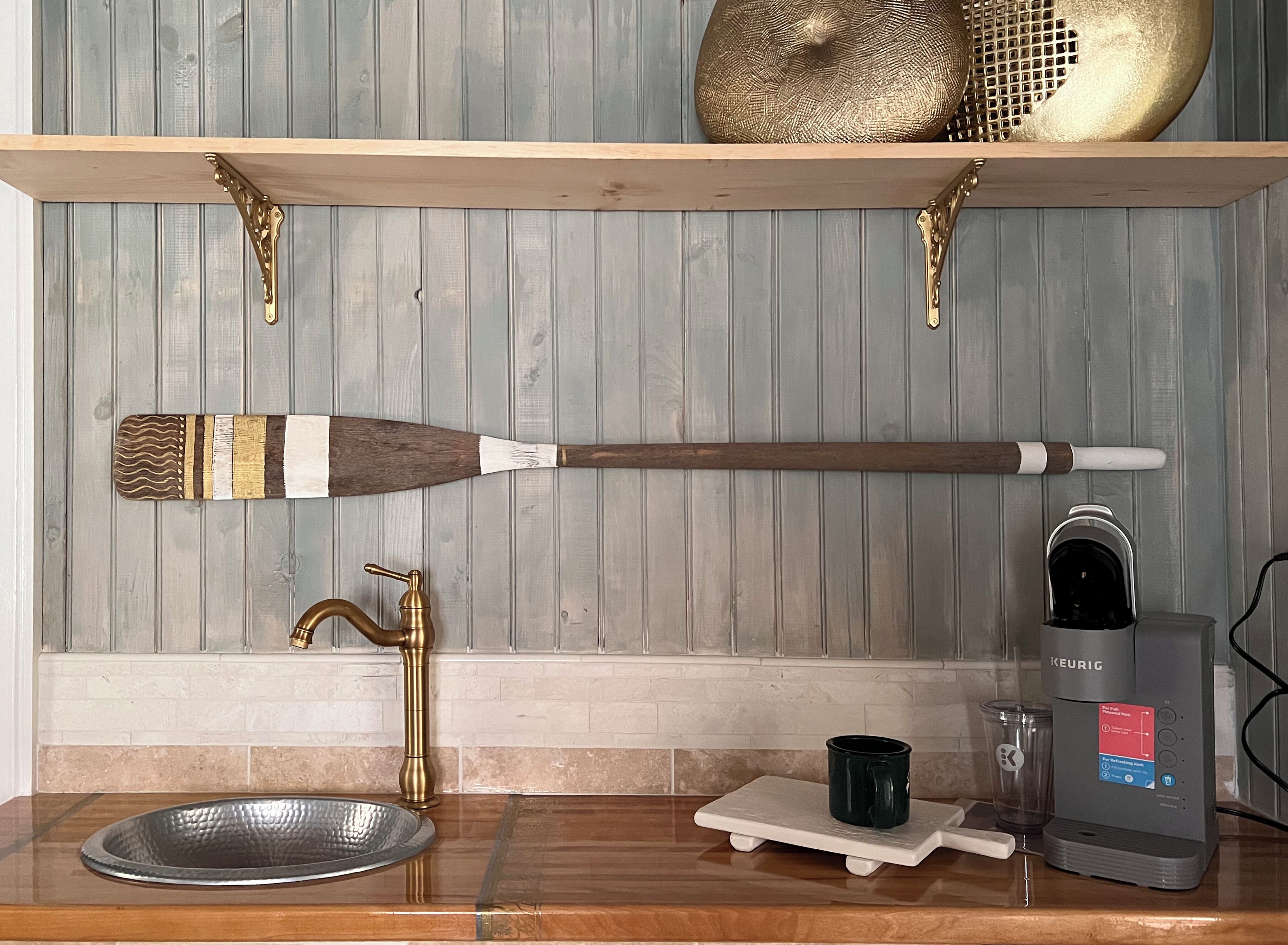 A kitchen with a wooden spoon, a coffee maker, and a metal bowl on the counter.