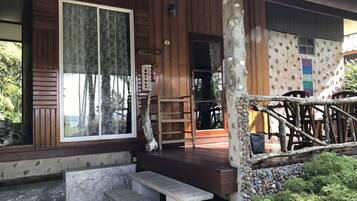 A wooden building with a porch, stone steps, and a stone wall.