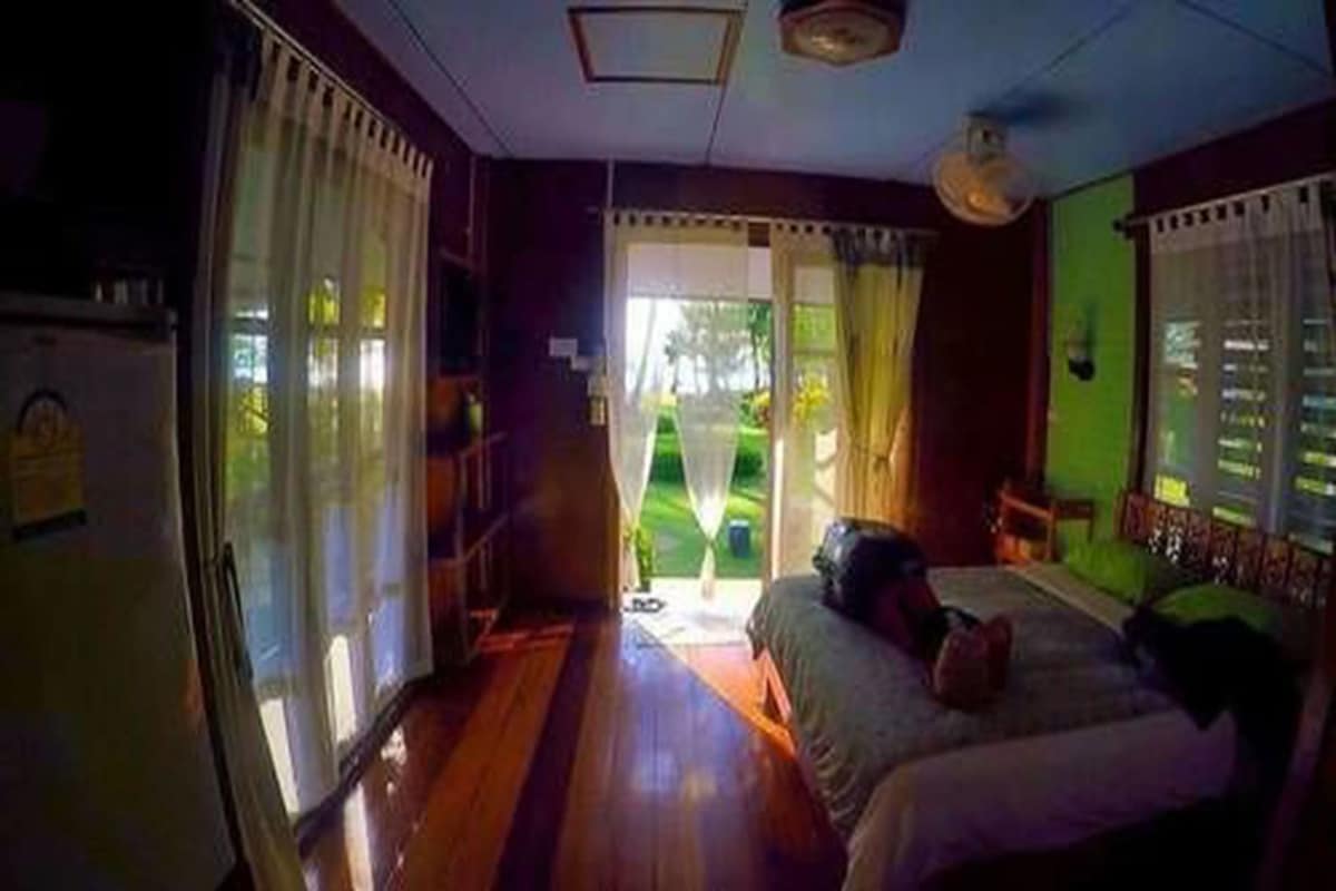 Ein Zimmer mit einem Bett, einem Fenster mit Vorhängen und Blick ins Freie.