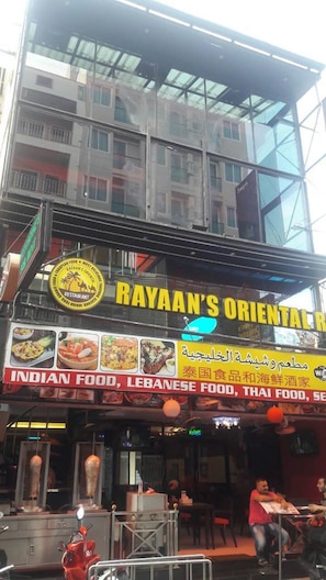 A restaurant with a glass facade and outdoor seating. - Rayaan Oriental Guest House & Restaurant (Patong)