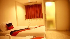 A hotel room with two beds, a sliding glass door, and a red curtain. - Rayaan Oriental Guest House & Restaurant (Patong)