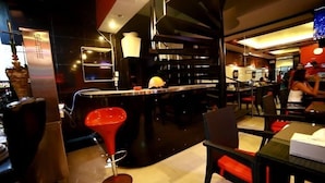 A modern bar area with a counter, stools, and a red bar stool. - Rayaan Oriental Guest House & Restaurant (Patong)