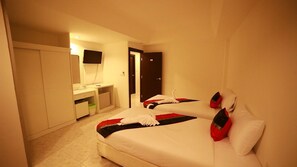 A hotel room with two beds, a desk, a mirror, a TV, and a door. - Rayaan Oriental Guest House & Restaurant (Patong)