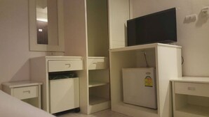 A compact hotel room with a small desk, a television on a cabinet, and a mirror on the wall. - Rayaan Oriental Guest House & Restaurant (Patong)