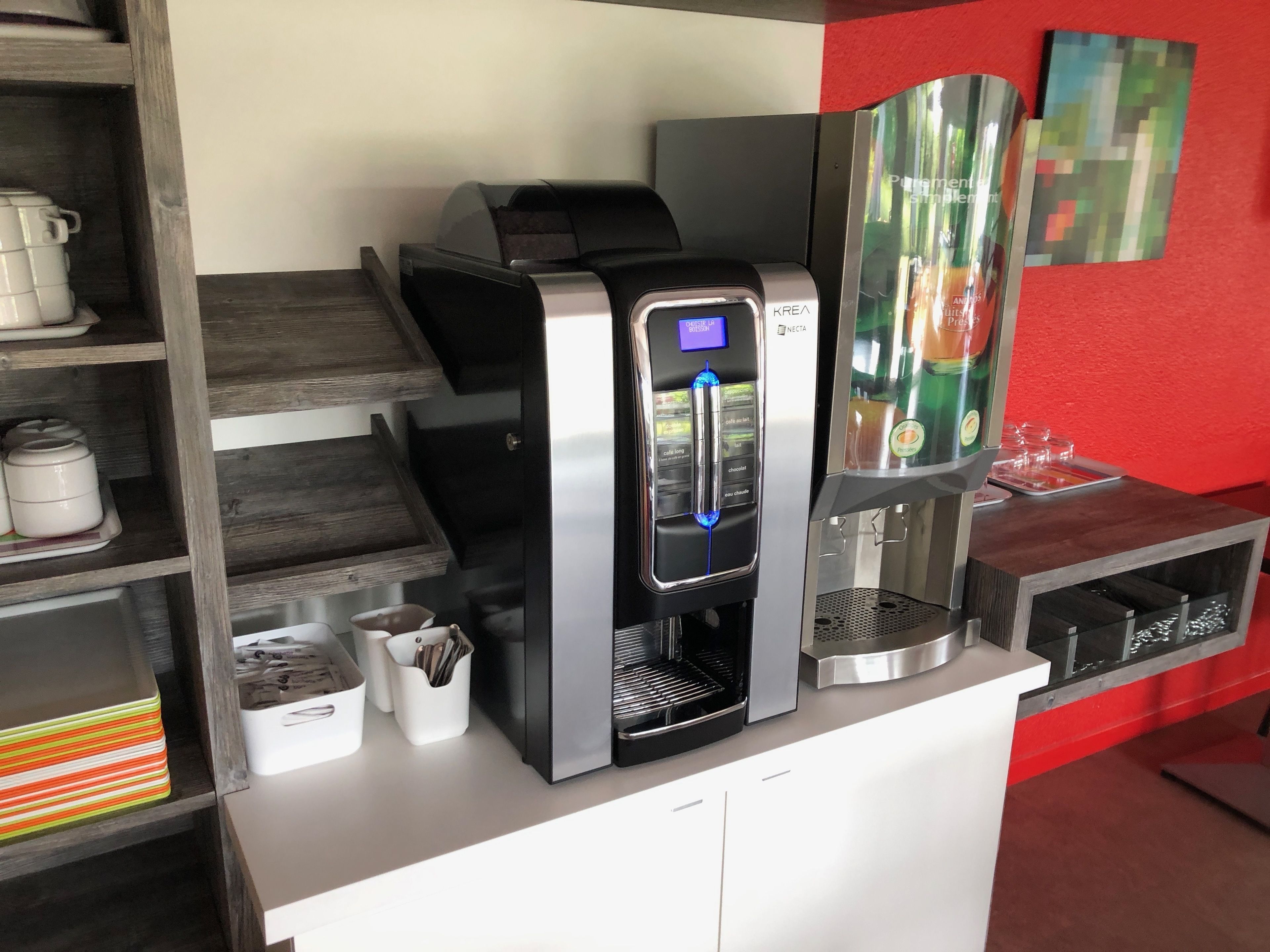 Una macchina per il caffè con display digitale, un erogatore di bevande e una caraffa in vetro su un bancone.