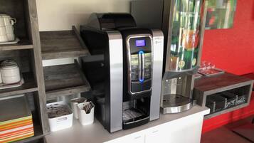 Una macchina per il caffè con display digitale, un erogatore di bevande e una caraffa in vetro su un bancone.