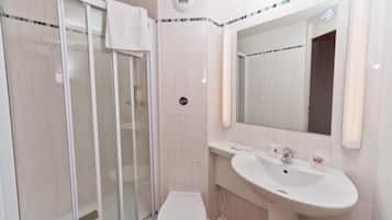 A bathroom with a glass-enclosed shower, a white toilet, and a sink with a mirror above it.