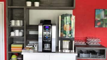Een koffiehoek met een koffieapparaat, een koelkast en planken met keukengerei.