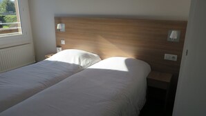 A double bed with white linens in a room with a wooden headboard and two bedside lamps. - Brit Hotel Rouen Sud / Val De Reuil (Val-de-Reuil)