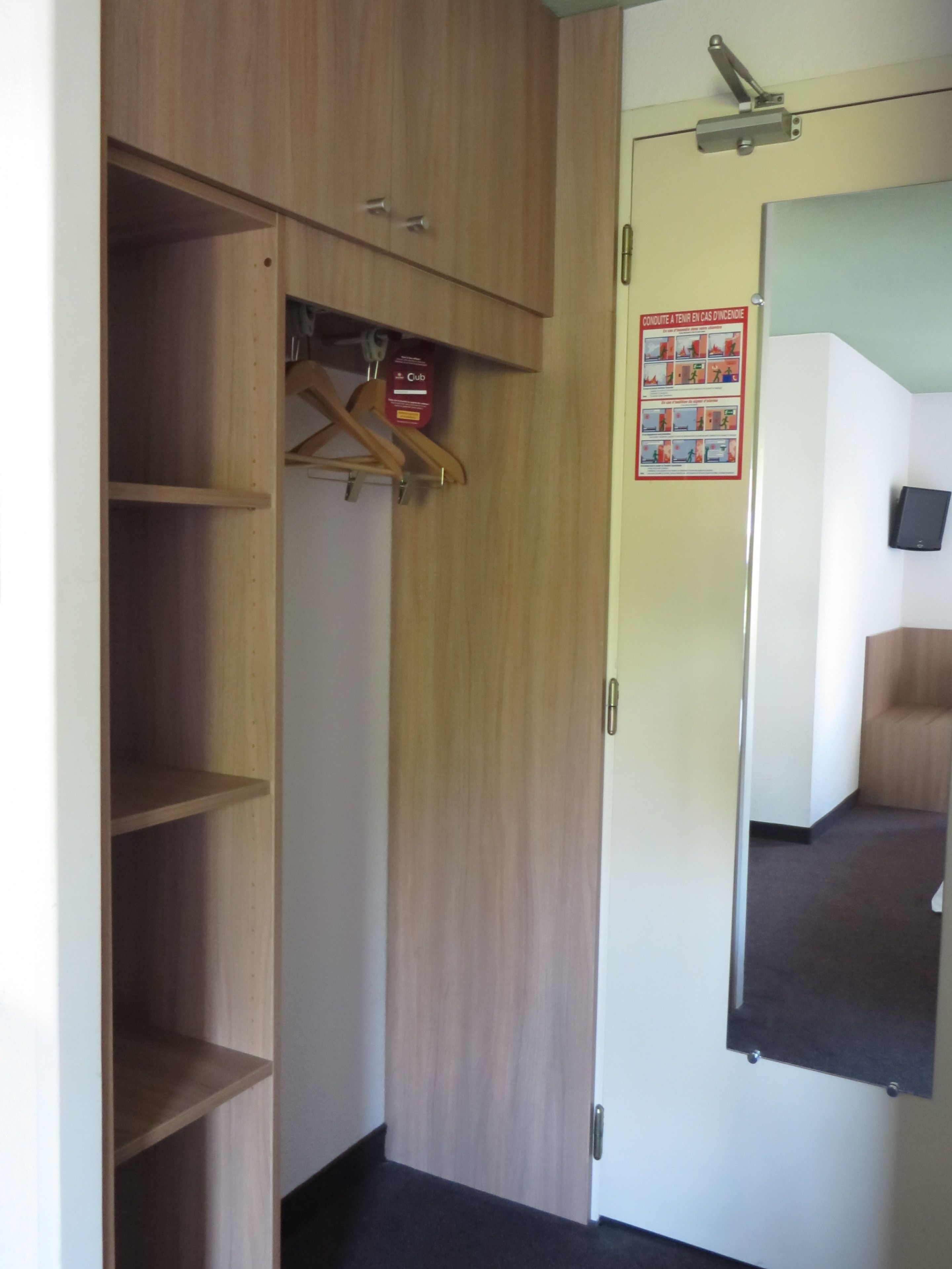 A wooden wardrobe with a hanging organizer and a mirror.
