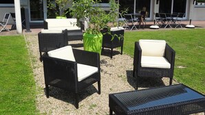An outdoor seating area with wicker furniture and umbrellas. - Brit Hotel Rouen Sud / Val De Reuil (Val-de-Reuil)