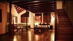 Una habitación amplia con techo alto, una cama grande y una escalera de madera.