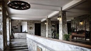 Vestíbulo de paredes de piedra con una escalera, un mostrador de recepción y un área de estar con un banco.