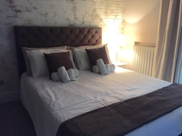A neatly made bed with a tufted headboard, white linens, and two rolled towels. - 29 Venti Luxury (Palermo)
