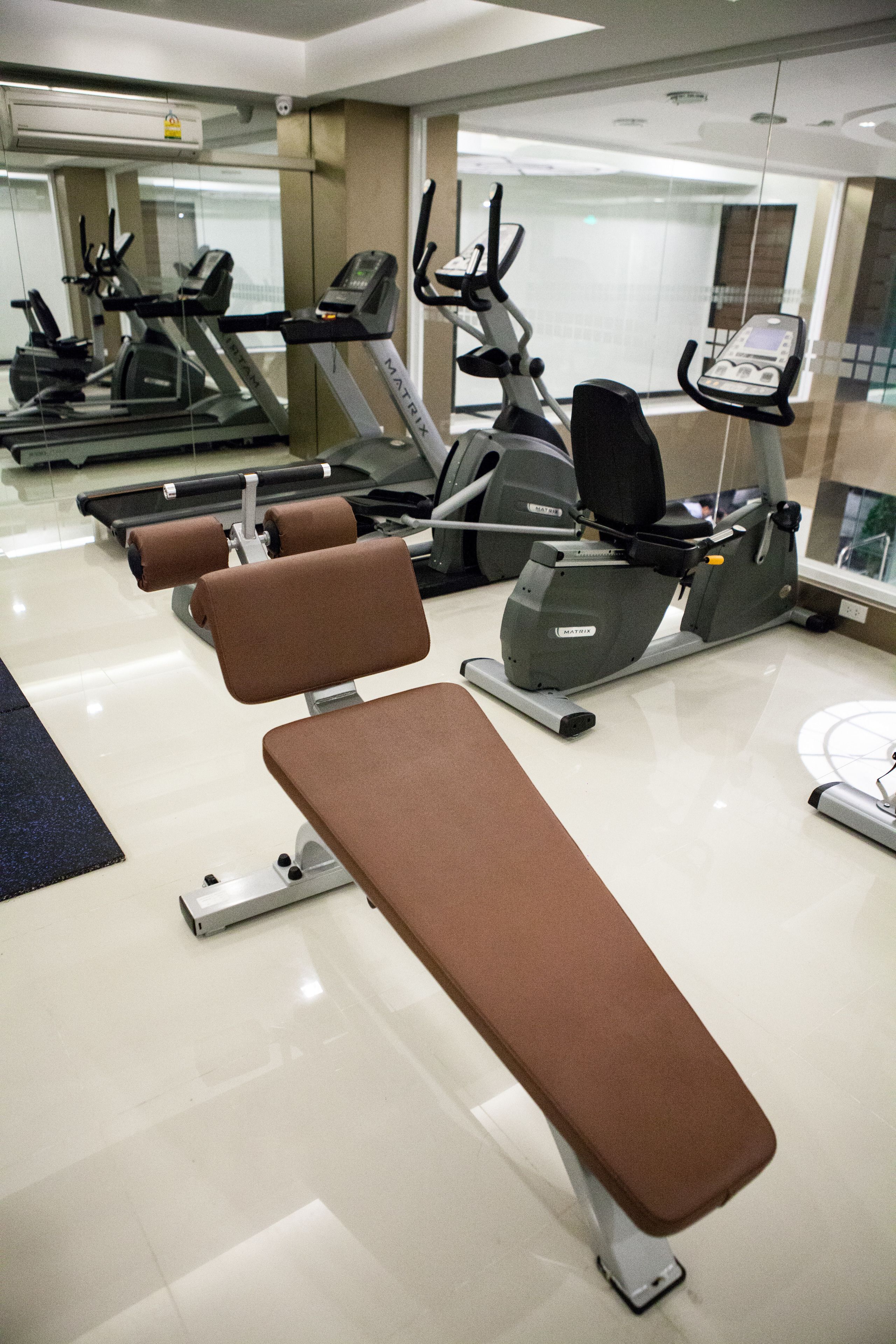 A gym with exercise equipment, including treadmills and stationary bikes, and a bench.