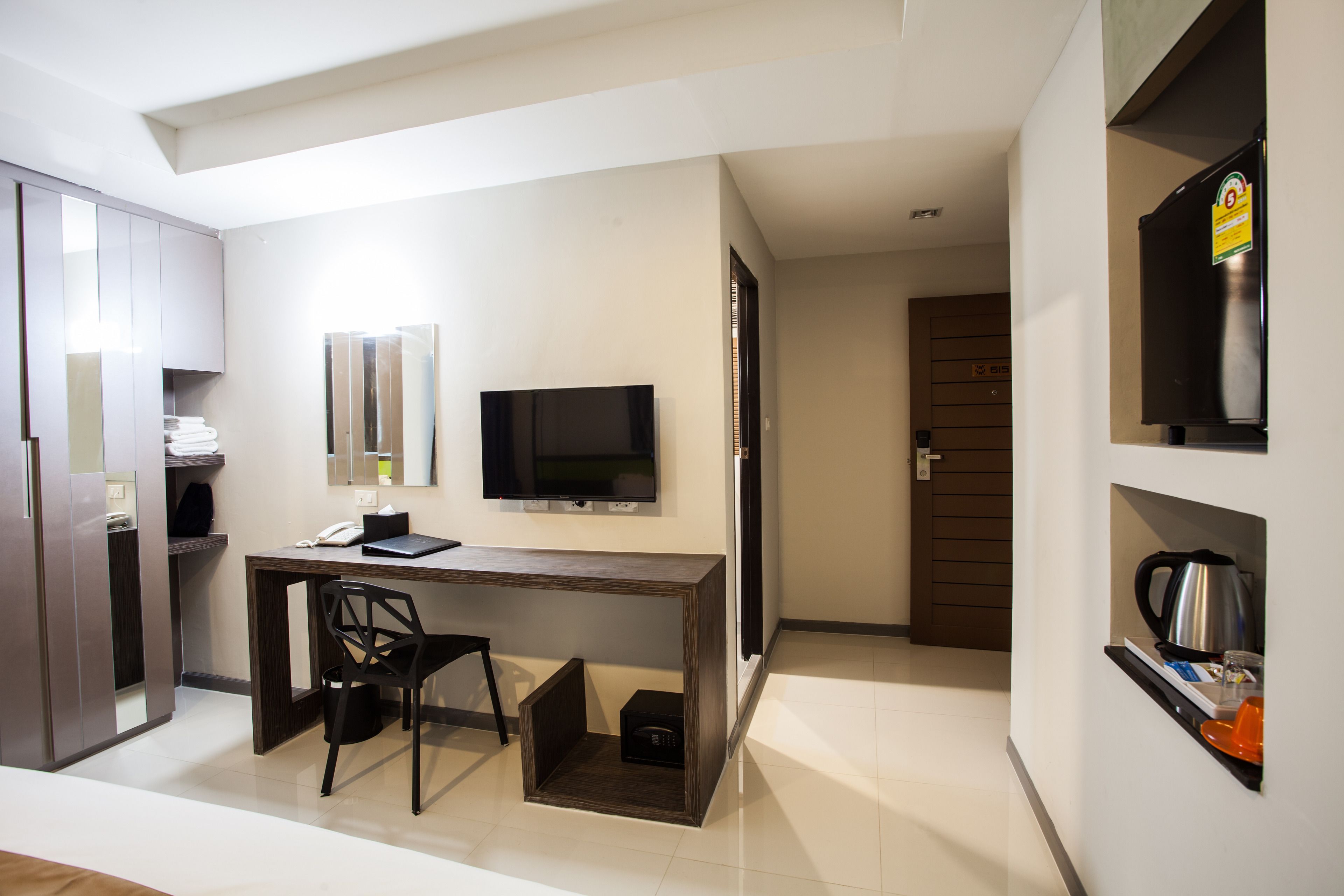 Une chambre d’hôtel moderne équipée d’un bureau, d’une chaise, d’une télévision et d’un coin cuisine.